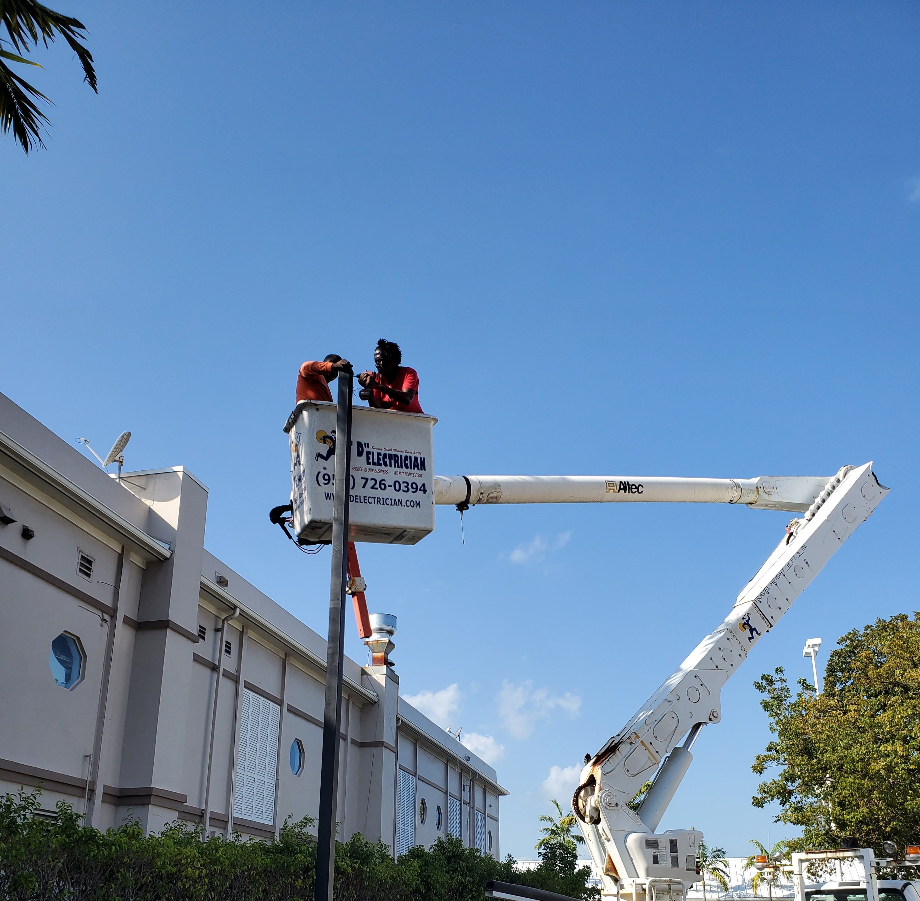 D Electrician Technical Services Inc. bucket truck lifting technicians to a pole light for repair
